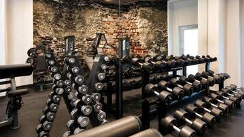 Ein Fitnessraum mit Gewichte, einer Bank und einer Ziegelwand im Hintergrund.
