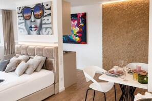 Ein Hotelzimmer mit einem Bett, einem Esstisch für zwei Personen und Bildern an den Wänden.