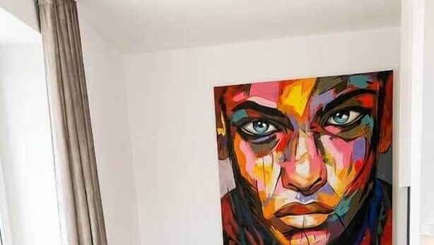 A modern living room with a beige sofa, a small round table, and a colorful abstract painting on the wall. - The Faces | Premium Studio | 207 (Berlin)