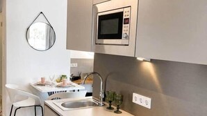 A modern kitchen with a built-in microwave, a sink, and a stovetop. - The Faces | Premium Studio | 207 (Berlin)