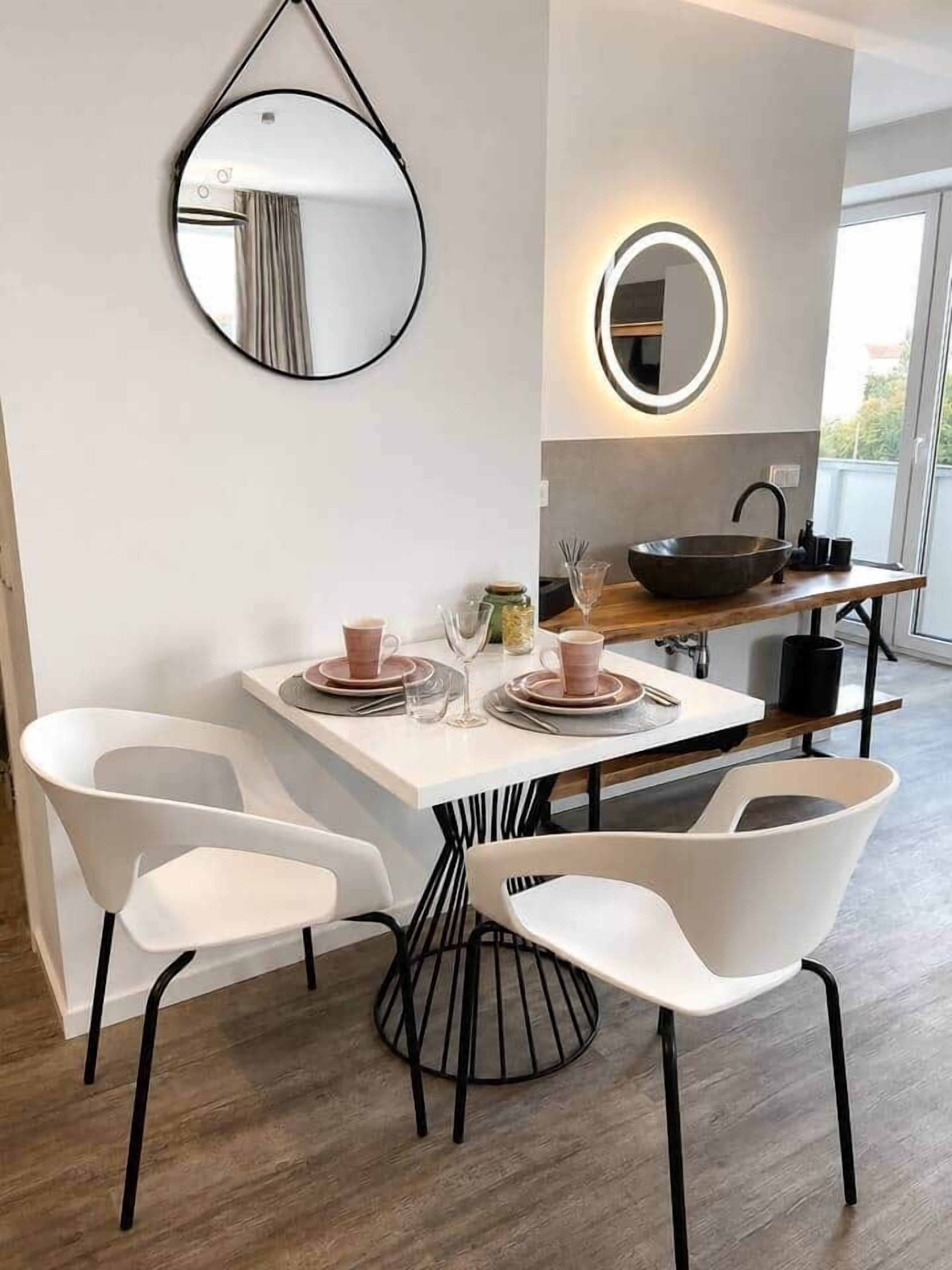 Eine moderne Küche mit Essbereich, inklusive Tisch mit Stühlen, einem hängenden Spiegel und einer Holz Arbeitsplatte.