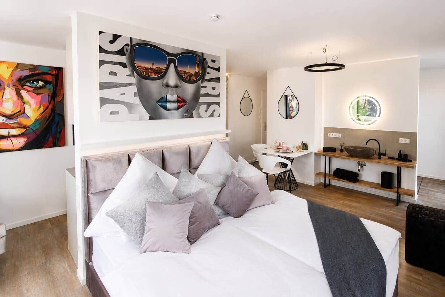 Ein modernes Schlafzimmer mit einem Bett, einem Nachttisch, einem Spiegel und Blick auf die Stadt.