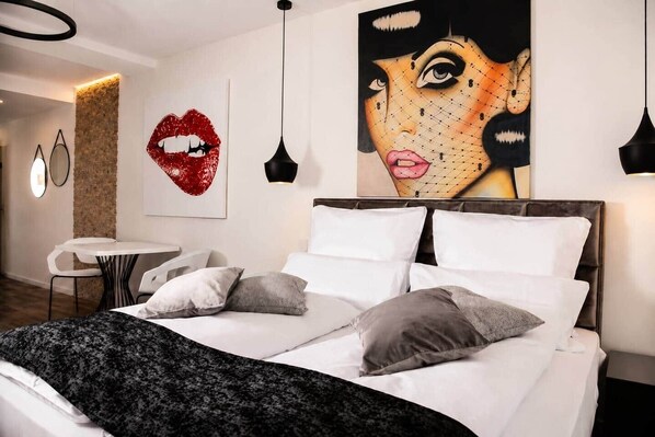 A modern bedroom with a bed, pillows, a round table, and two pendant lights. - The Faces | Premium Studio | Balcony | 301 (Berlin)