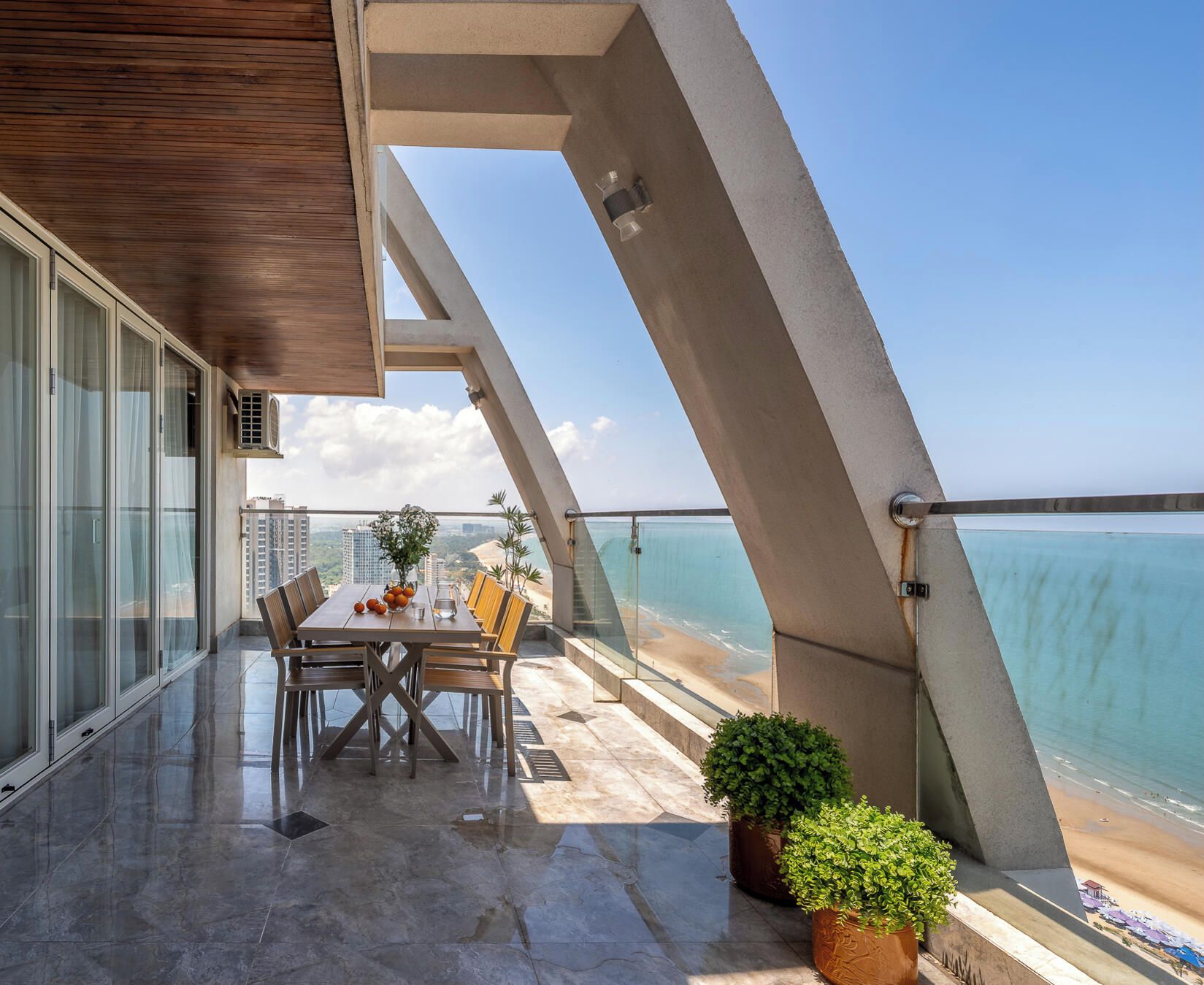 Un balcon moderne avec une table à manger, des chaises et des plantes en pot.