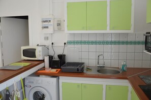 Eine kleine Küche mit Mikrowelle, Toaster, Spüle und grünen Schränken.