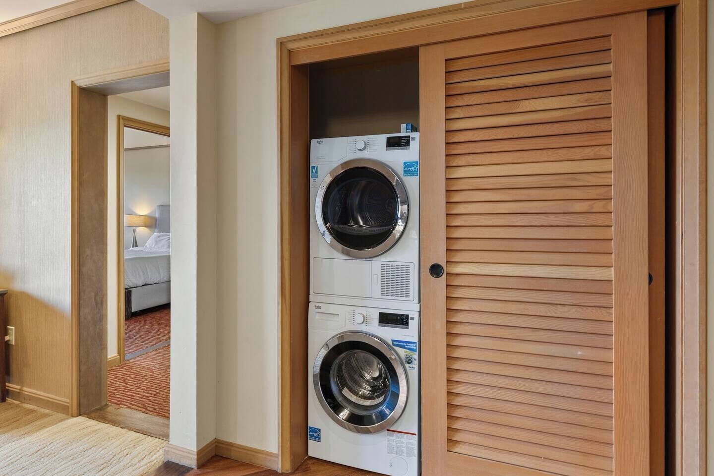 Een hotelkamer met een houten deur naar een wasserij met twee wasmachines.