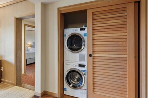 Habitación de hotel con una puerta de madera que da a un área de lavandería con dos lavadoras.