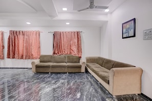 Una habitación con dos sofás, un ventilador de techo y un cuadro en la pared.