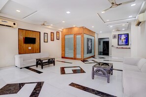 Una zona de recepción moderna con un sofá blanco, un panel de madera y un suelo de baldosas con diseños geométricos.