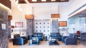 A modern lobby with seating areas, a fireplace, and a glass wall. - Treebo Trend Ambassador (Ahmedabad)