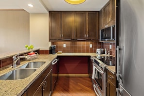 A modern kitchen with granite countertops, stainless steel appliances, and wooden cabinets.