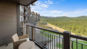 A balcony with wicker furniture overlooking a mountainous landscape.