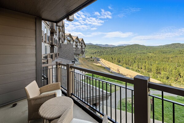 A balcony with wicker furniture overlooking a mountainous landscape.