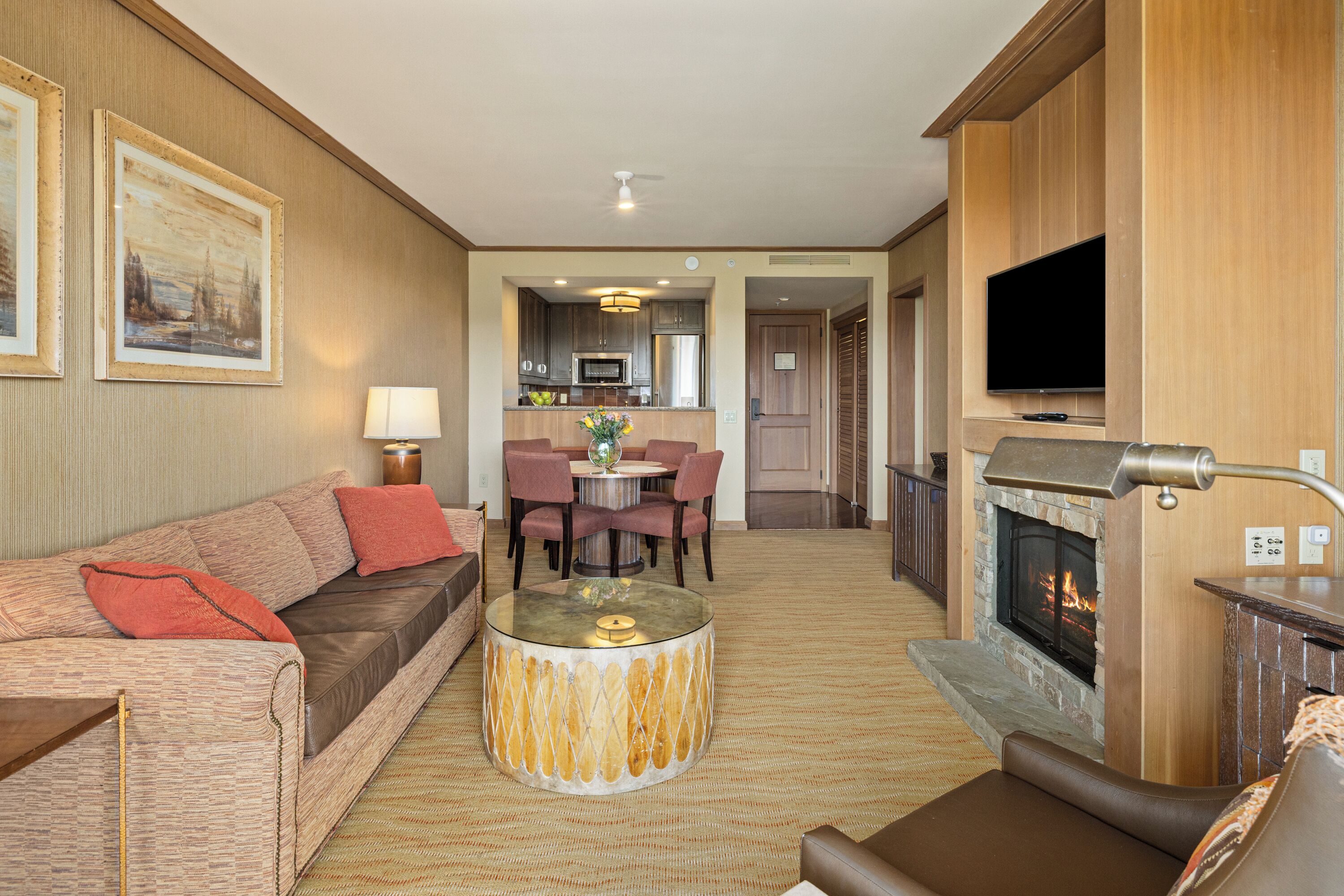 A living room with a fireplace, a dining area, and a kitchen in the background.