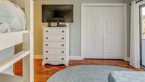 Un dormitorio con cama, cómoda, televisor y puerta.