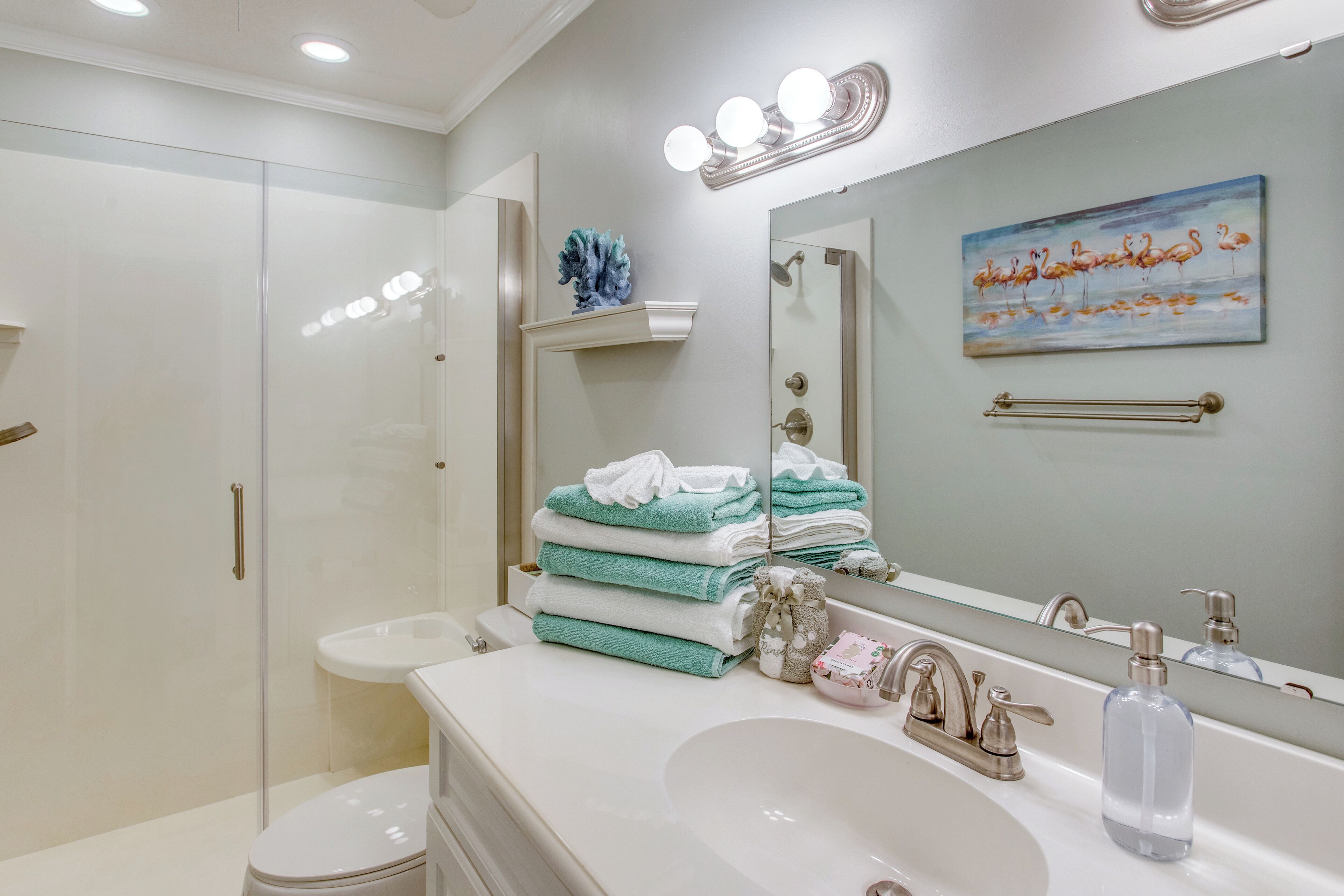 A modern bathroom with a glass-enclosed shower, a white sink, and a vanity with a mirror.