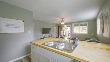 Una cocina con un lavamanos doble, encimera de madera y un ventilador de techo.
