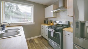 A kitchen with a double sink, a stove, a microwave, and a refrigerator. - Walk to Ski Lifts! Apt in Heart of Red River (Red River)