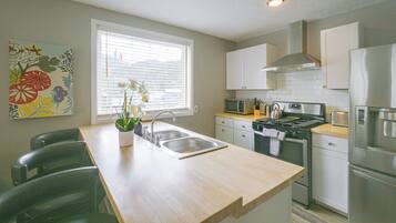 Una cocina moderna con una isla central, electrodomésticos de acero inoxidable y una ventana con persianas.