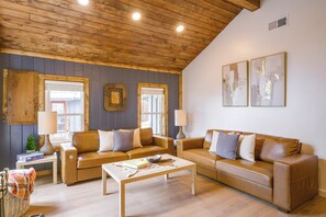 A cozy living room with a wooden ceiling, two leather sofas, a coffee table, and two wall-mounted lamps. - Walk to Main St: Red River Lodge w/ Ski Views! (Red River)