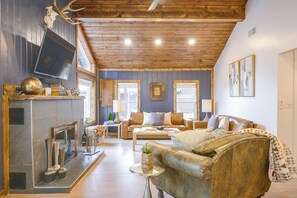 A cozy living room with a fireplace, leather sofa, and a television. - Walk to Main St: Red River Lodge w/ Ski Views! (Red River)
