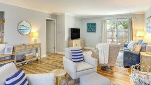 Sala de estar con un sofá, televisor y vista al exterior.
