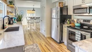Una cocina moderna con electrodomésticos de acero inoxidable, piso de madera y un comedor con mesa y sillas.