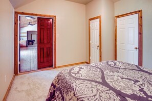 A bedroom with a bed, two doors, and a hallway leading to a bathroom. - Gated Ranch Retreat Near Lakes & Frisco (Aubrey)
