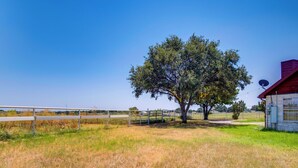 A rural landscape with a large tree, a fenced area, and a building with a red roof. - Gated Ranch Retreat Near Lakes & Frisco (Aubrey)