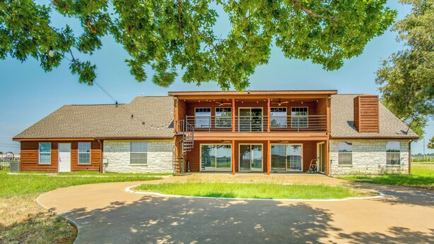 A two-story building with a stone facade, large windows, and a covered front porch. - Gated Ranch Retreat Near Lakes & Frisco (Aubrey)