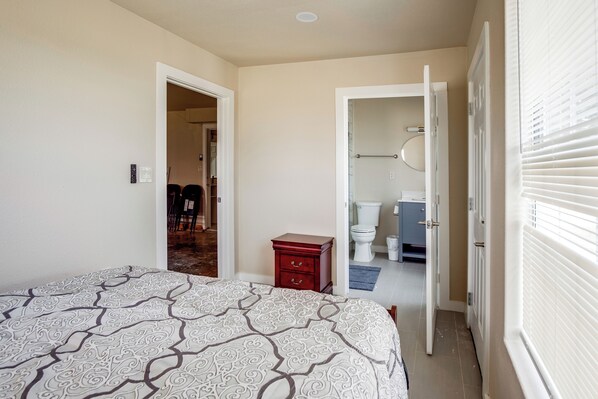 A bedroom with a bed, a dresser, and a bathroom visible through an open door.