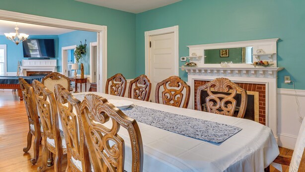 A dining room with a long table, ornate chairs, a fireplace, and a television in the background. - Walk to Beach & Oceanside Trails! Family Retreat (York Harbor)