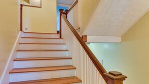 A staircase with wooden steps and a wooden handrail, leading to a landing with a white textured ceiling. - Walk to Beach & Oceanside Trails! Family Retreat (York Harbor)
