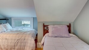 A bedroom with two beds, a window, and a sloped ceiling. - Walk to Beach & Oceanside Trails! Family Retreat (York Harbor)