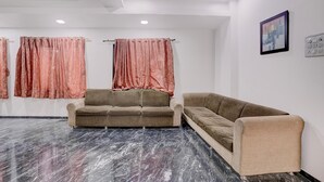 A room with two sofas, a ceiling fan, and a painting on the wall.