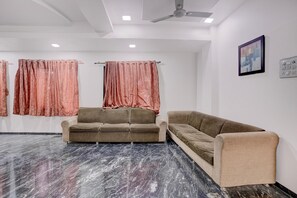 A room with two sofas, a ceiling fan, and a painting on the wall.