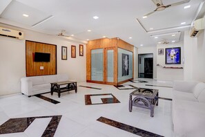 A modern reception area with a white sofa, a wooden partition, and a tiled floor with geometric patterns.