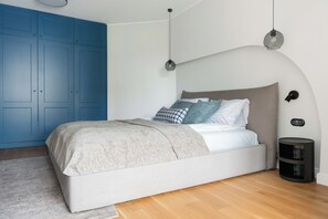 A bedroom with a bed, a blue wardrobe, a bedside table, and a wall-mounted lamp. - Blue Loft Sopot Beachside  (Sopot)