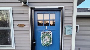 Una casa con una porta blu, un cartello di benvenuto e una cassetta delle lettere.