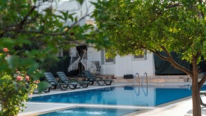 A swimming pool with lounge chairs and a tree in the foreground. - Green Garden Göynük Hotel  (Kemer)