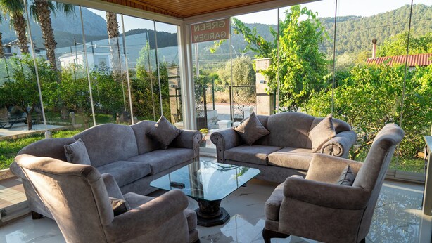 A modern living room with a glass coffee table, two sofas, and armchairs. - Green Garden Göynük Hotel  (Kemer)