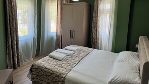 A bedroom with a bed, a wardrobe, and curtains. - Green Garden Göynük Hotel  (Kemer)