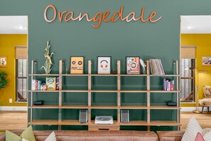 A room with a bookshelf, a couch, and a wall with the word 'Orangedale' above it. - Hidden Sanctuary with Heated Saltwater pool, fire pit, and koi pond (St. Augustine)