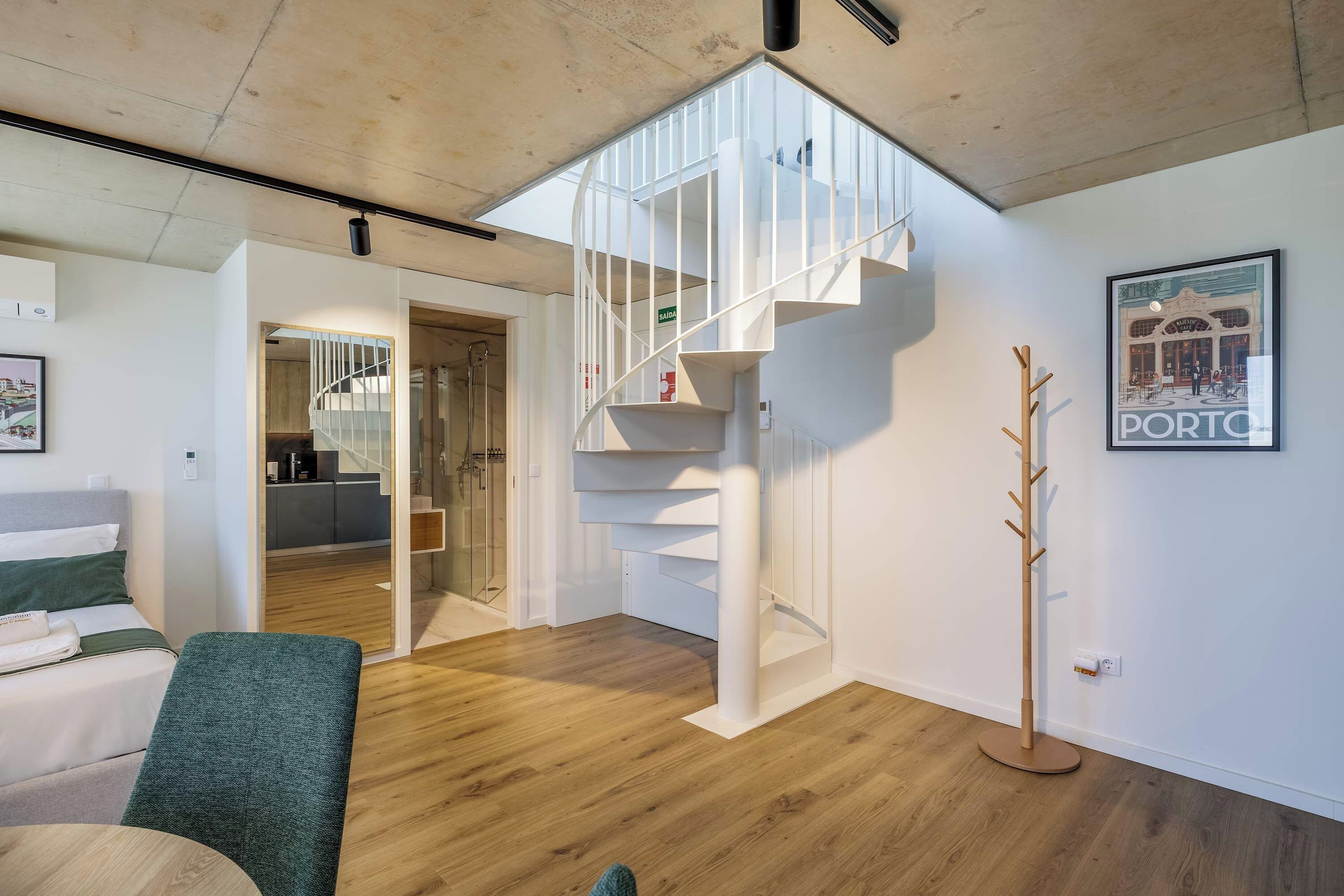 A modern interior with a staircase, a coat rack, and a framed picture of a cafe.