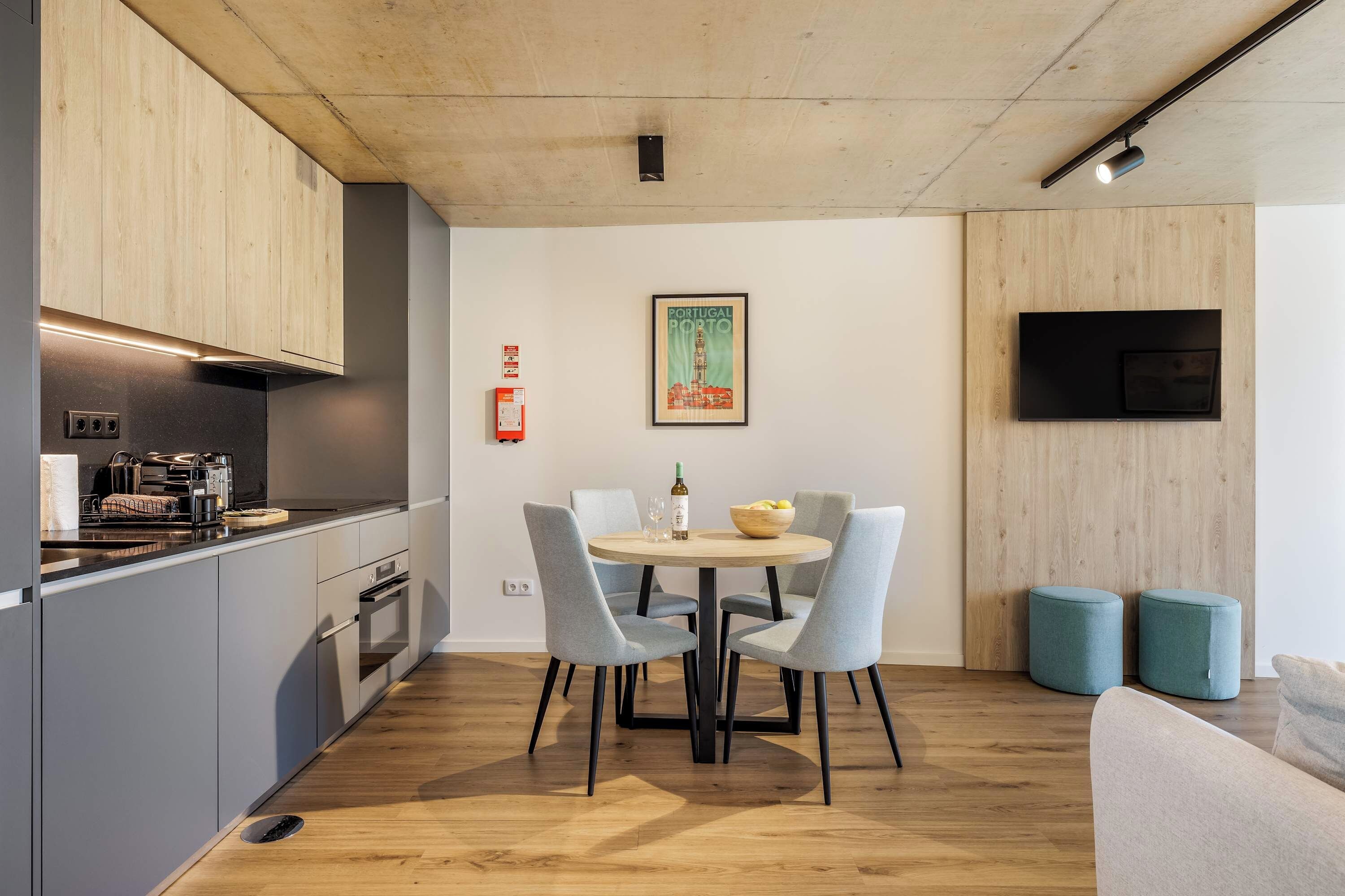 Una cocina moderna con zona de comedor, un televisor de pantalla plana en la pared y un cuadro con vista a la ciudad.
