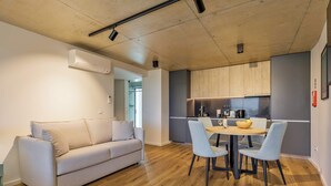 Et moderne opholdsrum med sofa, spisebord, stole og et køkkenområde.