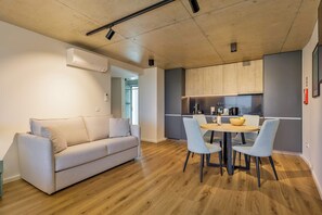 A modern living space with a sofa, dining table, chairs, and a kitchen area. - Marina da Afurada Apartments - Miguel Cervantes (Vila Nova de Gaia)