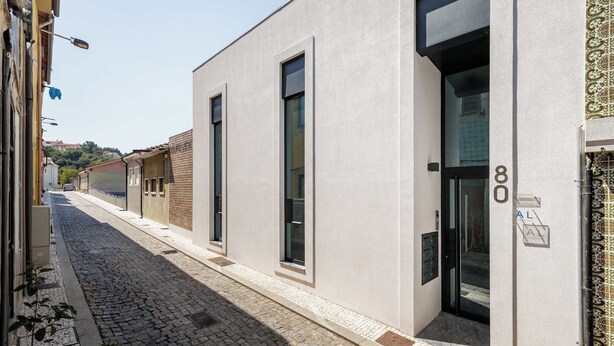 En bygning med en moderne facade, store vinduer og en brostensbelagt gade.