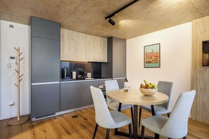 A modern kitchen with grey cabinets, a round dining table with chairs, and a painting on the wall. - Stylish Waterfront Apt Near Douro, Dining, & Beach (Vila Nova de Gaia)
