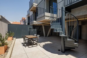 Eine moderne Außenpatio mit Wendeltreppe, Esstisch und Stühlen.